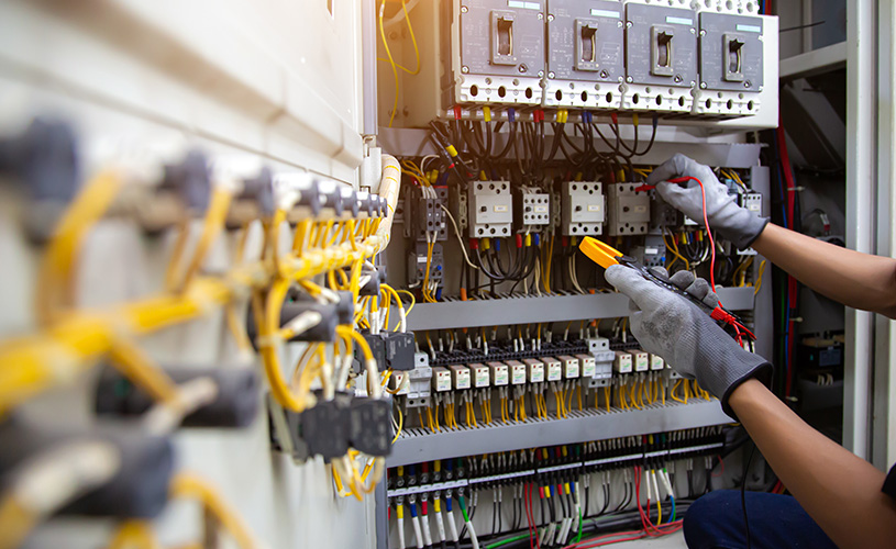 Elektrofachkraft prüft mit einem Messgerät eine elektrische Verteilung im Rahmen der Sicherheitsstromversorgung eines Gebäudes